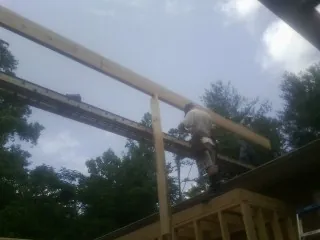 Carpenter setting a ridge beam over a new addition frame — Ice Dam Removal by Roofing Brothers in Natick