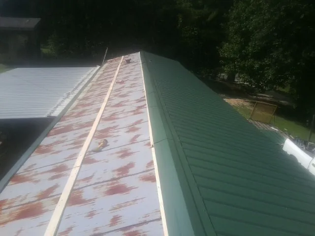 Old rusted panels beside newly installed green metal roofing — Wind Damage Roof Repair by Roofing Brothers in Natick