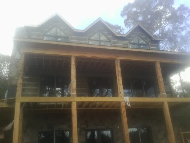 Dormers and porch framing on a large log home under construction — Roof Coating work by our crew in Natick