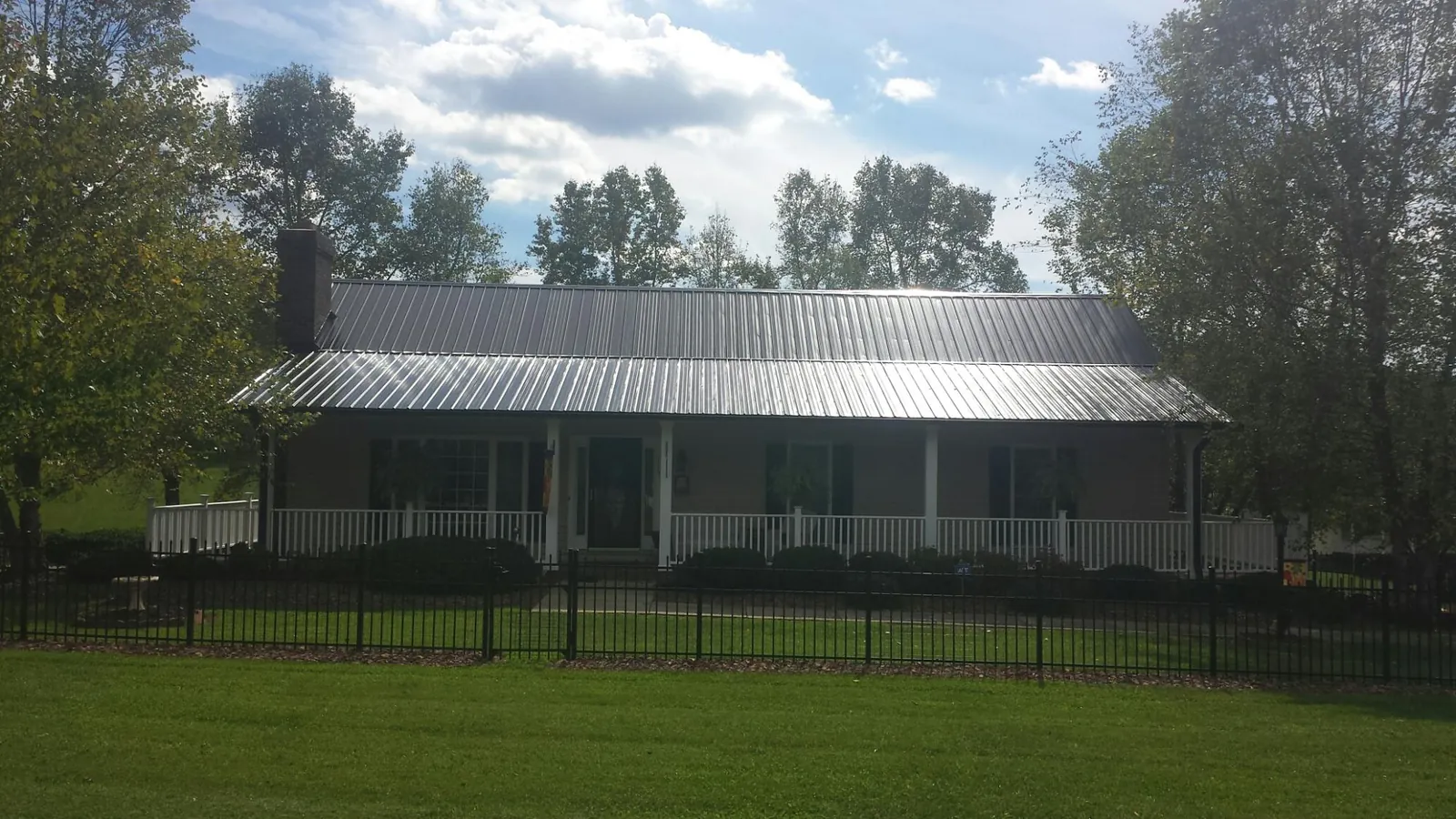 Gray metal roof on a brick ranch with a full width front porch — Gutter Guard Installation work by our crew in Natick