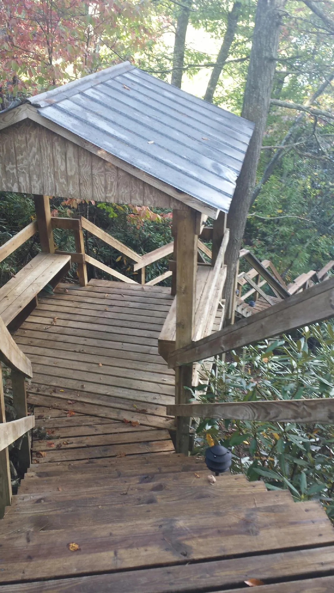 Metal roofed shelter over wooden steps on a wooded walkway — Skylight Repair & Installation work by our crew in Natick
