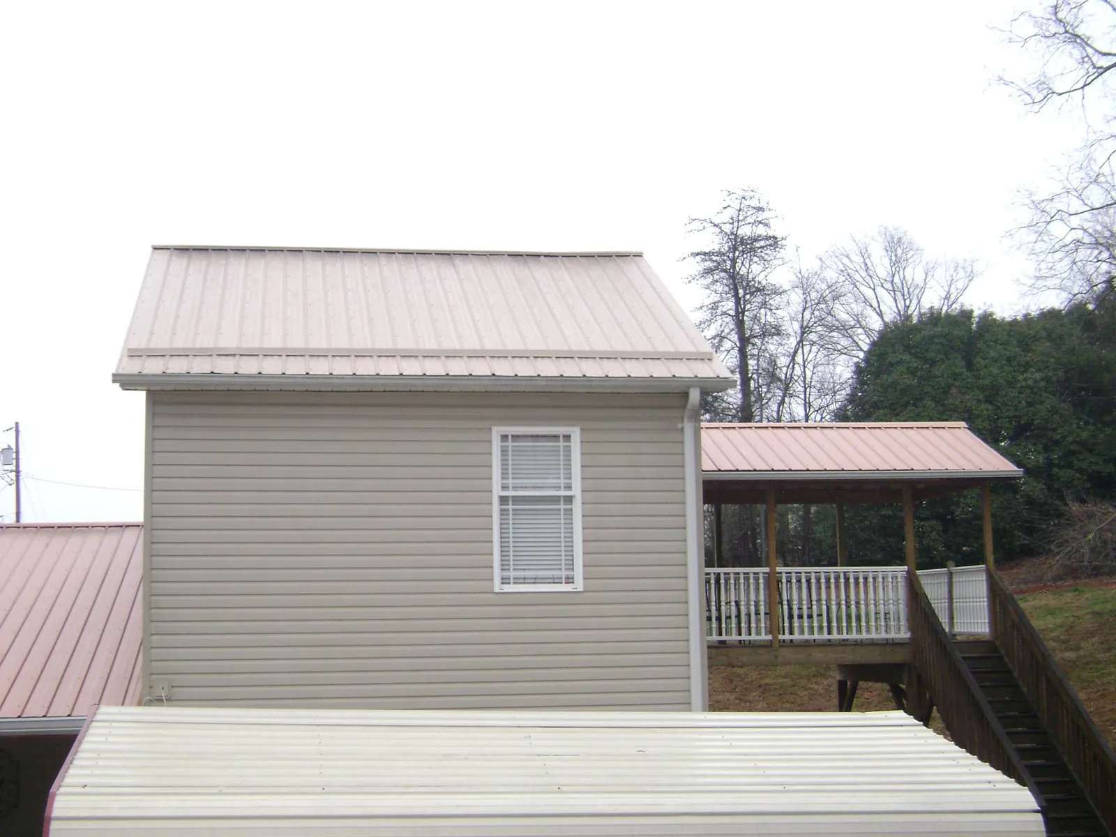 Tan metal roofs on a two story addition and attached porch, from a Roof Replacement job in Natick